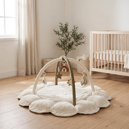Nid d'éveil Nuage coloris Ivoire Sauge (crème et vert olive) avec arche et jouets suspendus, posé dans une chambre d'enfant